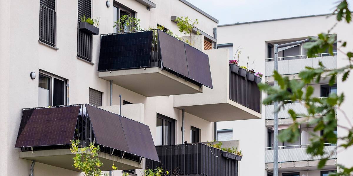 Balkone moderner Wohngebäude mit Solarpanels und bepflanzten Blumenkästen – nachhaltige Energiegewinnung im städtischen Wohnbau.