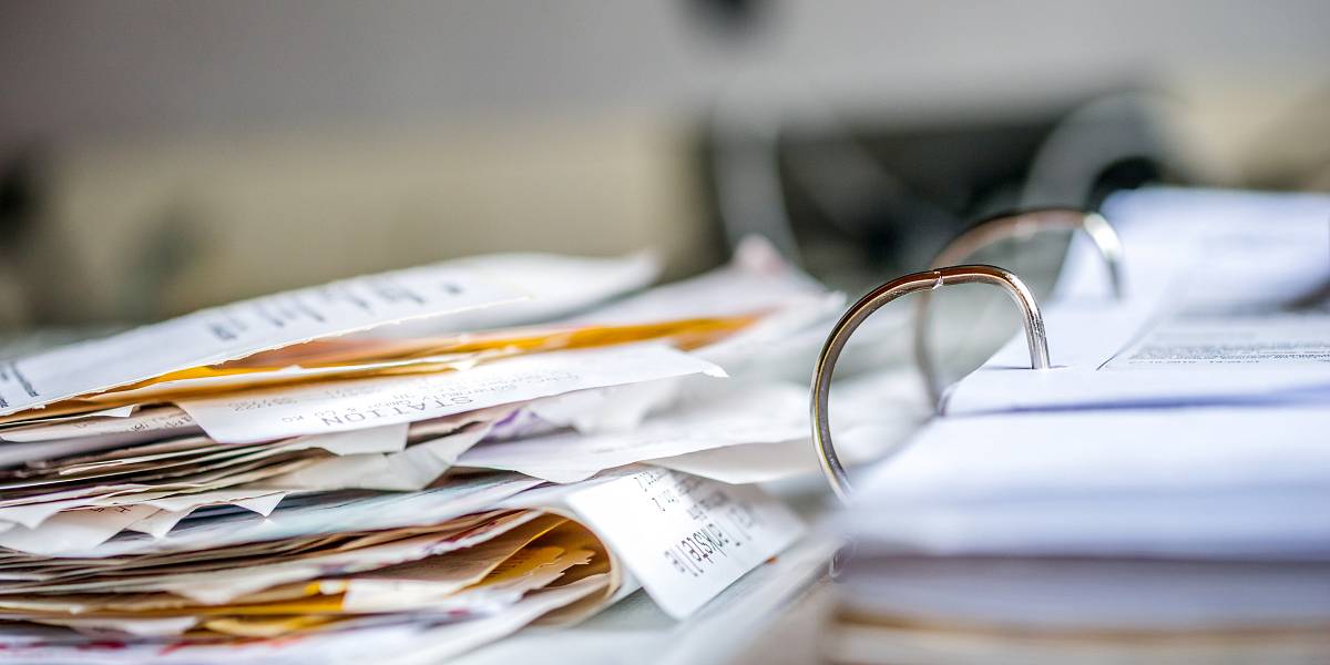 Unordentlicher Stapel aus Belegen und Dokumenten in einem offenen Ordner – symbolisch für steuerliche Unterlagen beim Immobilienkauf.