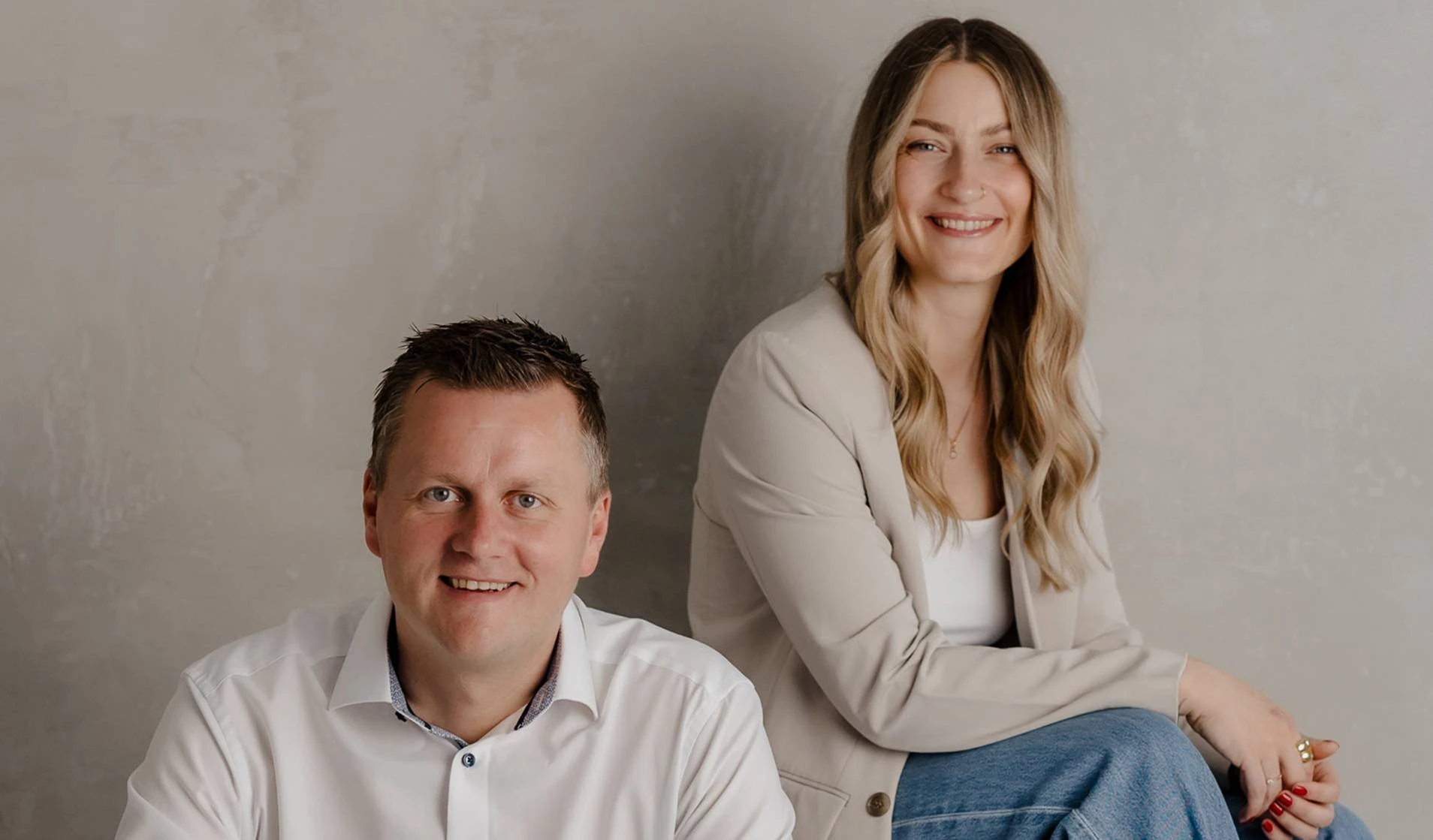 Zwei freundlich lächelnde Immobilienexperten von Peter Vogt Immobilien vor neutralem Hintergrund.