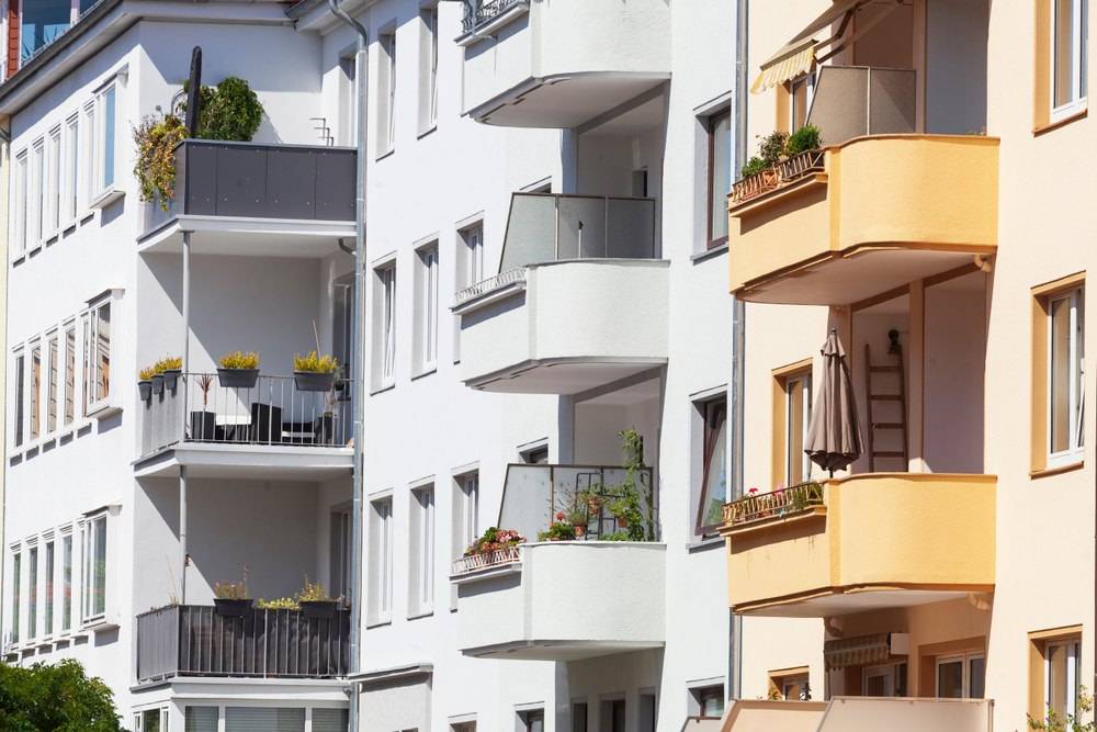 Mehrfamilienhäuser mit weißen und gelben Fassaden, Balkonen und Pflanzen in Hannover bei Sonnenschein.