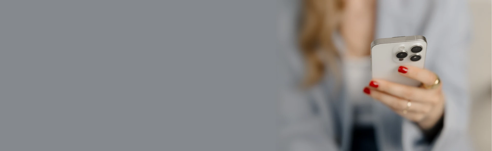 Frau mit rotem Nagellack hält ein Smartphone – Kontaktaufnahme per Handy