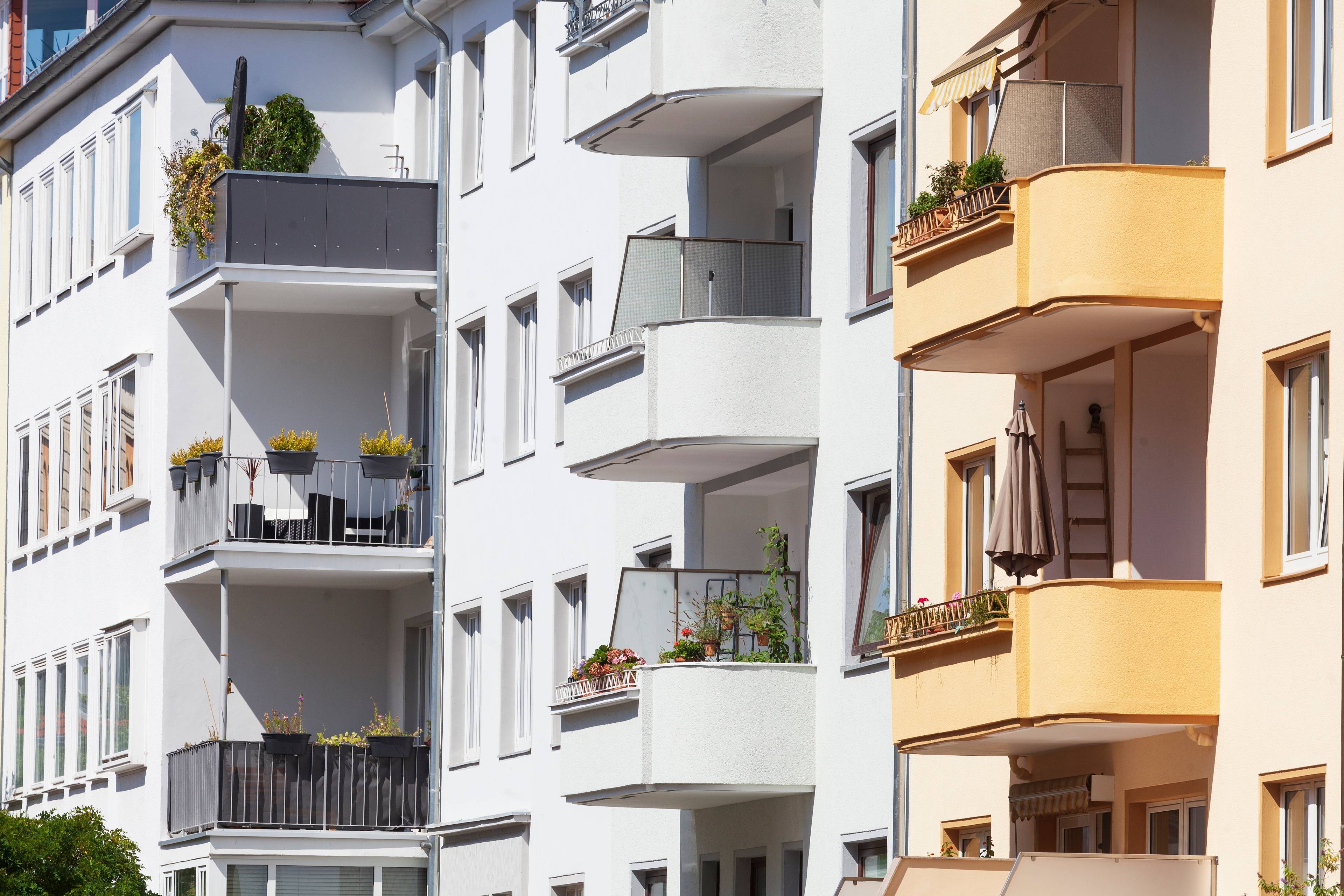 Mehrfamilienhäuser mit weißen und gelben Fassaden, Balkonen und Pflanzen in Hannover bei Sonnenschein.