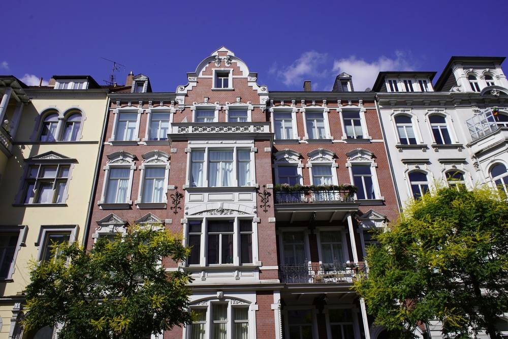 Sanierte historische Mehrfamilienhäuser in Hannover mit detailreicher Fassade und Straßenbäumen