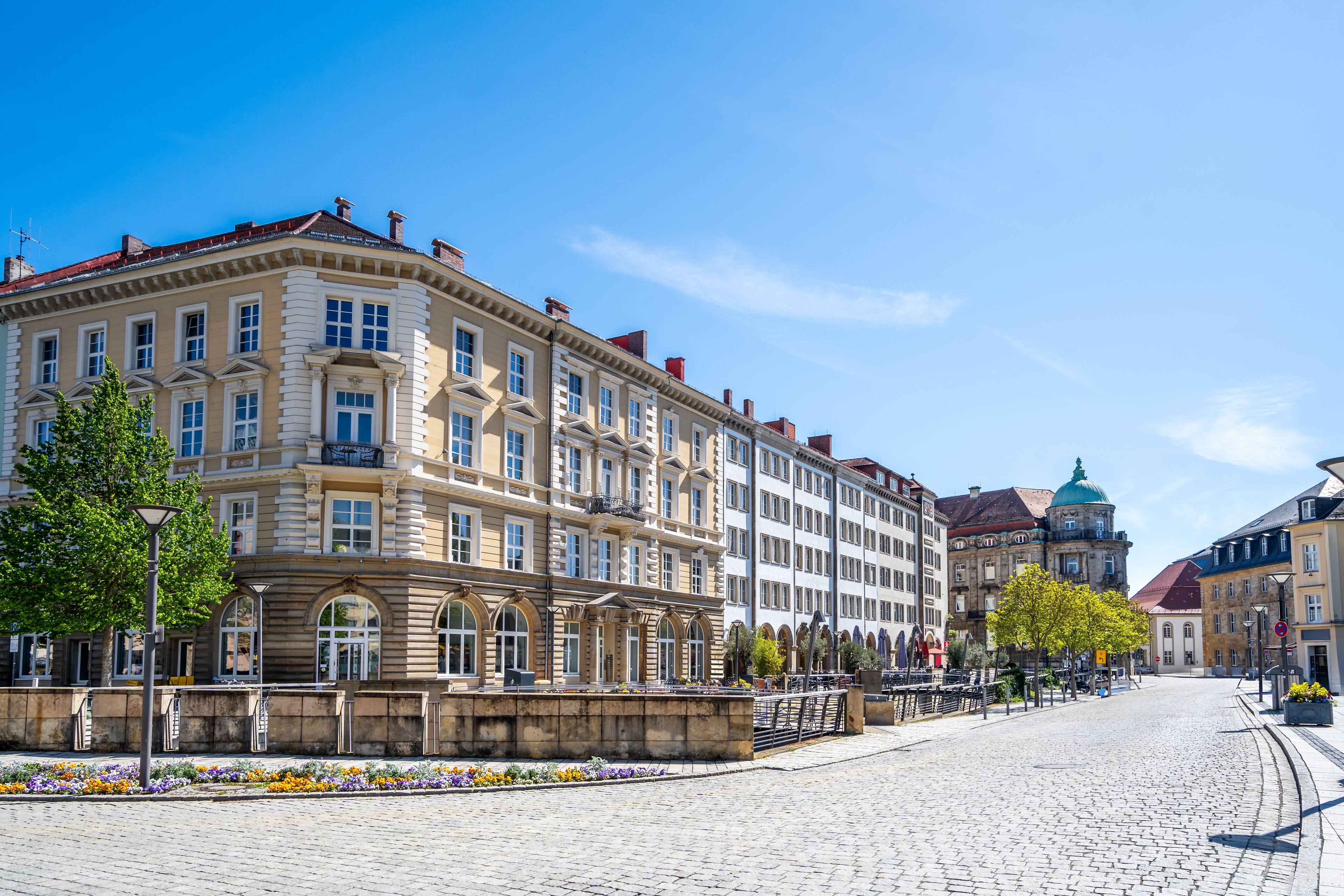 Sanierte Altbaufassade mit großen Fenstern und klassischem Steinmauerwerk am zentralen Stadtplatz von Bayreuth bei sonnigem Wetter