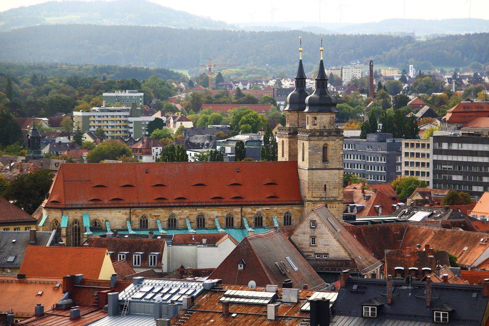 Panoramablick über die Dächer von Bayreuth mit der markanten Stadtkirche und grünem Umland im Hintergrund