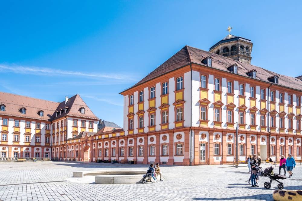 Modernes Mehrfamilienhaus in Berlin mit Balkonen und großen Fenstern bei blauem Himmel.