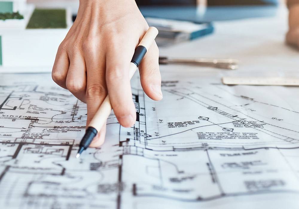 Architekt oder Planer zeigt mit Stift auf technischen Bauplan – Fokus auf Immobilienbewertung und Grundriss