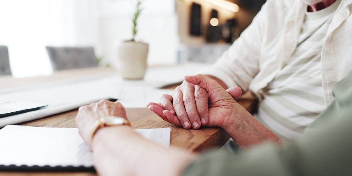 Beratungsgespräch zur Altersvorsorge: Zwei Personen besprechen Finanzunterlagen am Tisch in ruhiger Wohnatmosphäre.