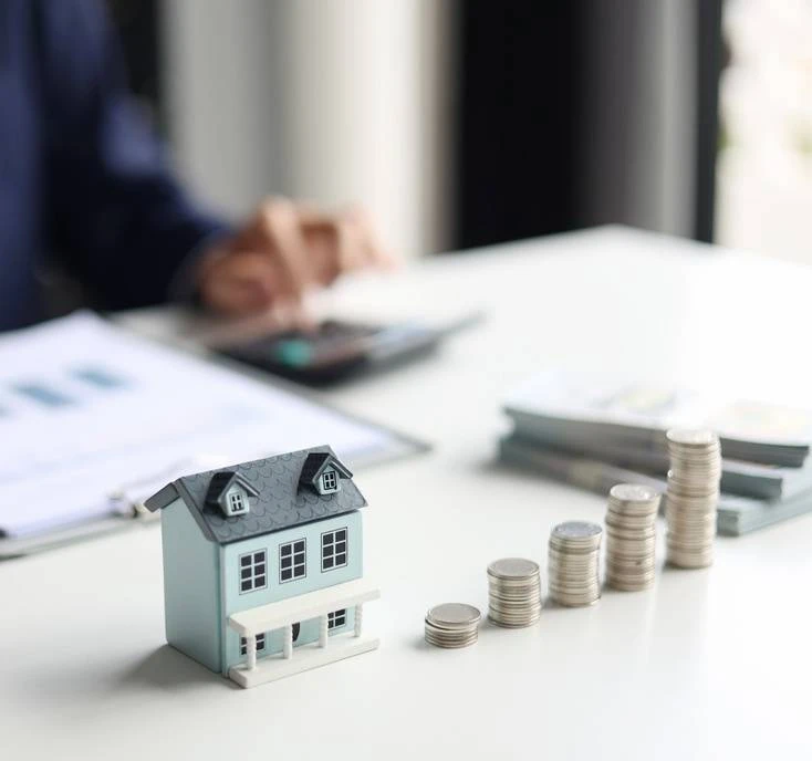 Hausmodell mit gestapelten Münzen als Symbol für steigende Rendite und wirtschaftliche Bewertung einer Immobilieninvestition