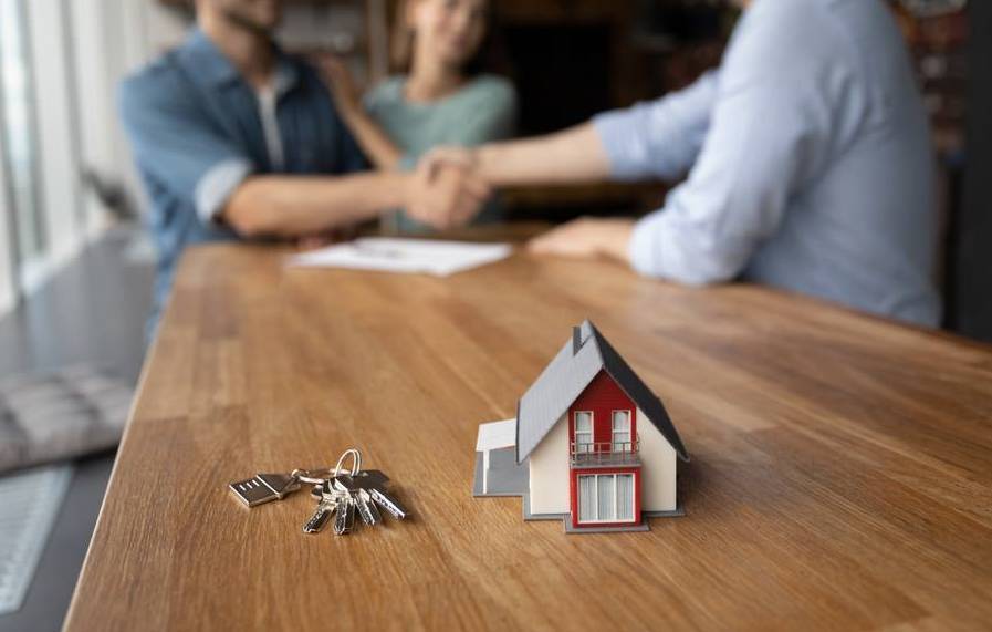 Hausmodell und Schlüssel auf einem Tisch bei einem Beratungsgespräch zum Immobilienkauf in Bayreuth