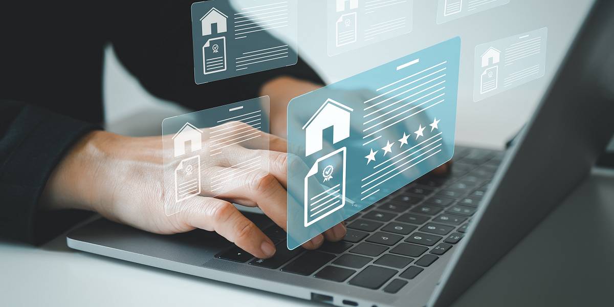 Hände tippen auf Laptop-Tastatur, darüber schwebende digitale Symbole von Immobilien und Dokumenten – Symbolbild für Digitalisierung in der Immobilienbranche.