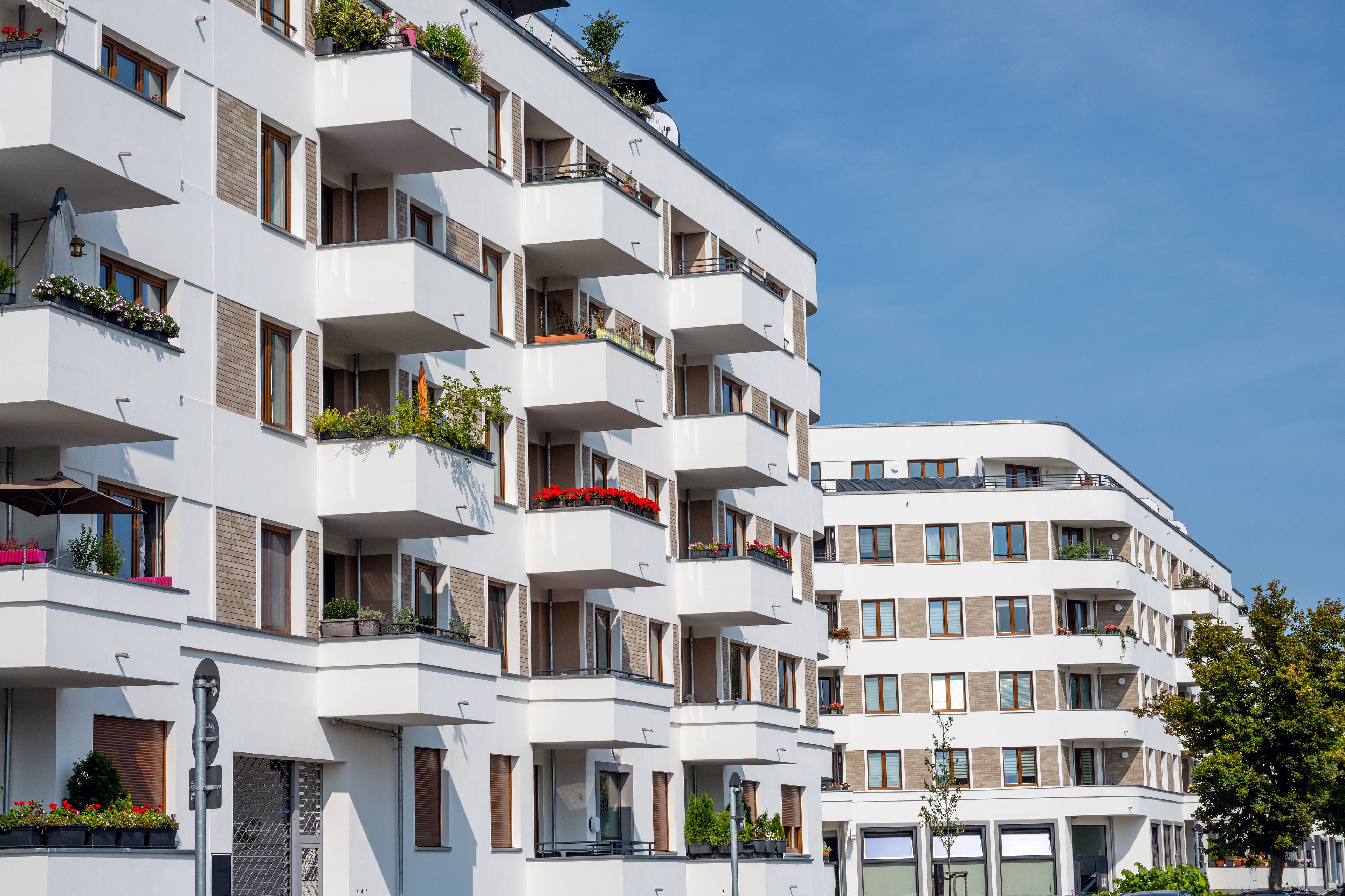 Modernes Mehrfamilienhaus in Berlin mit Balkonen und begrünten Fassaden bei sonnigem Wetter – Symbol für professionelle Immobilieninvestments.