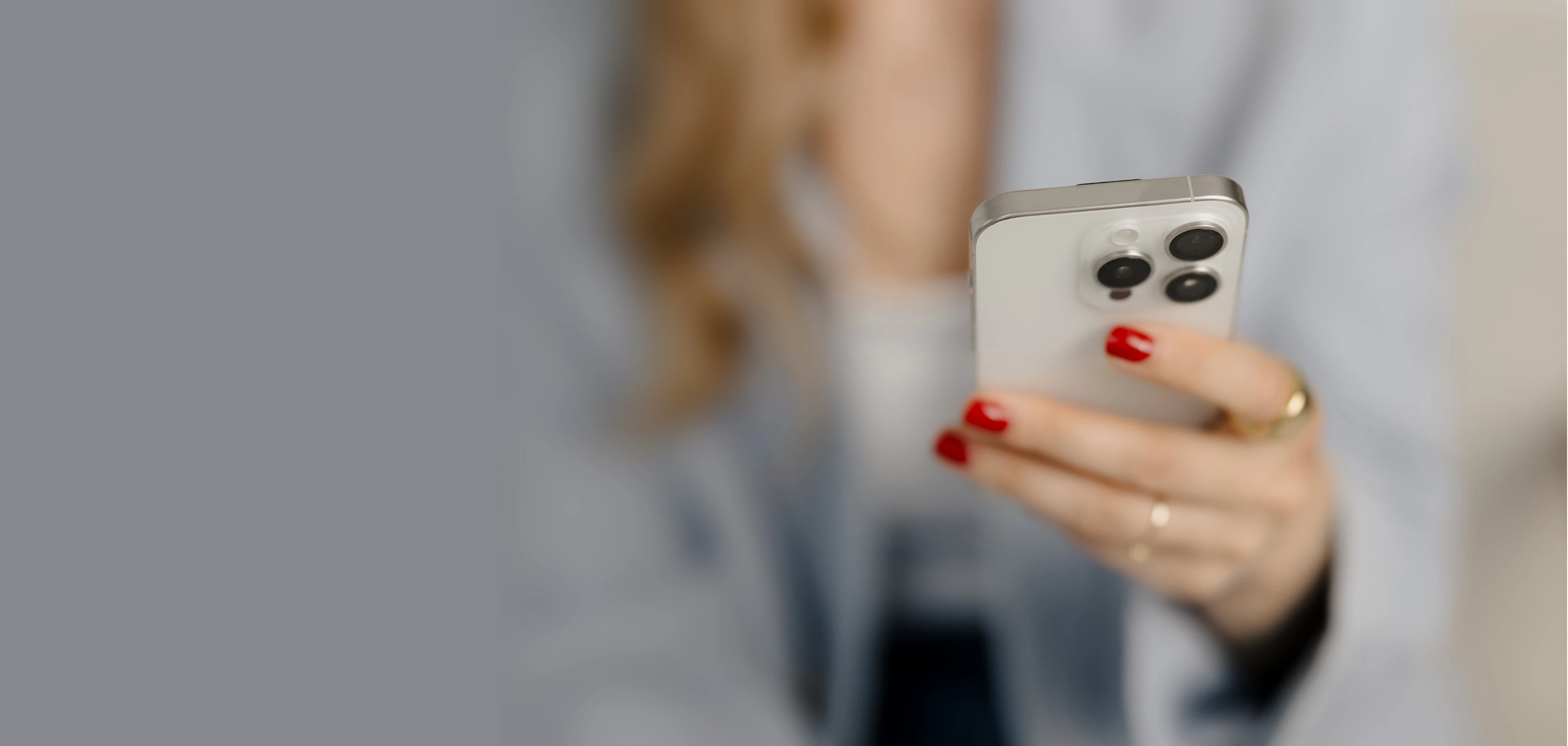 Frau in Business-Outfit hält Smartphone in der Hand – moderner Kontakt zur Immobilienberatung