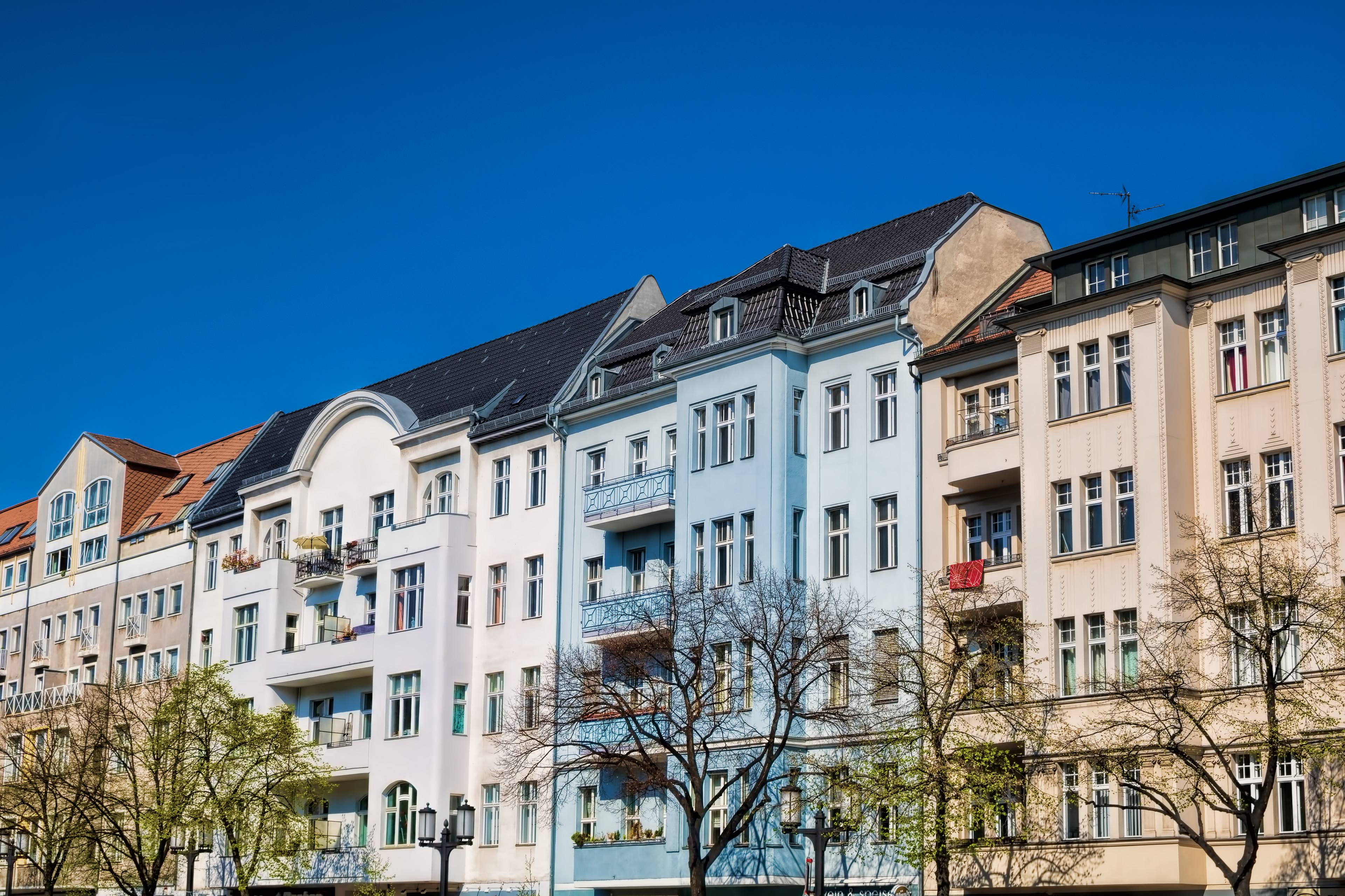 Sanierte Altbaufassade mit Balkonen und blauen Akzenten in Berlin bei strahlendem Himmel