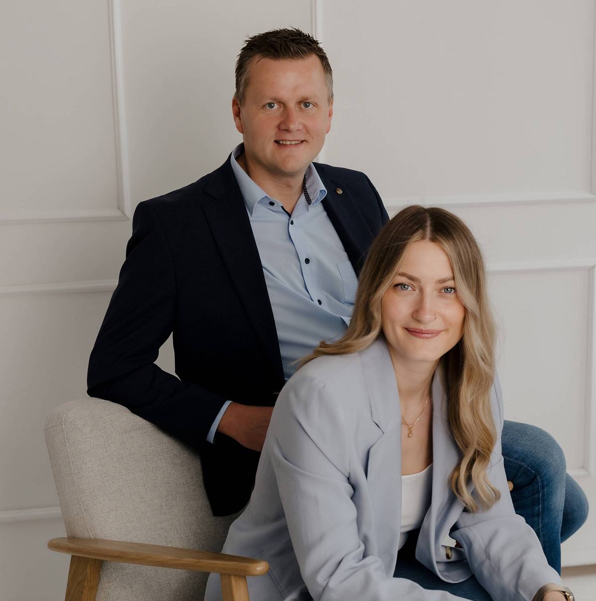 Zwei Immobilienexperten sitzen entspannt vor hellem Hintergrund – professionelles Teamfoto von Peter Vogt Immobilien.