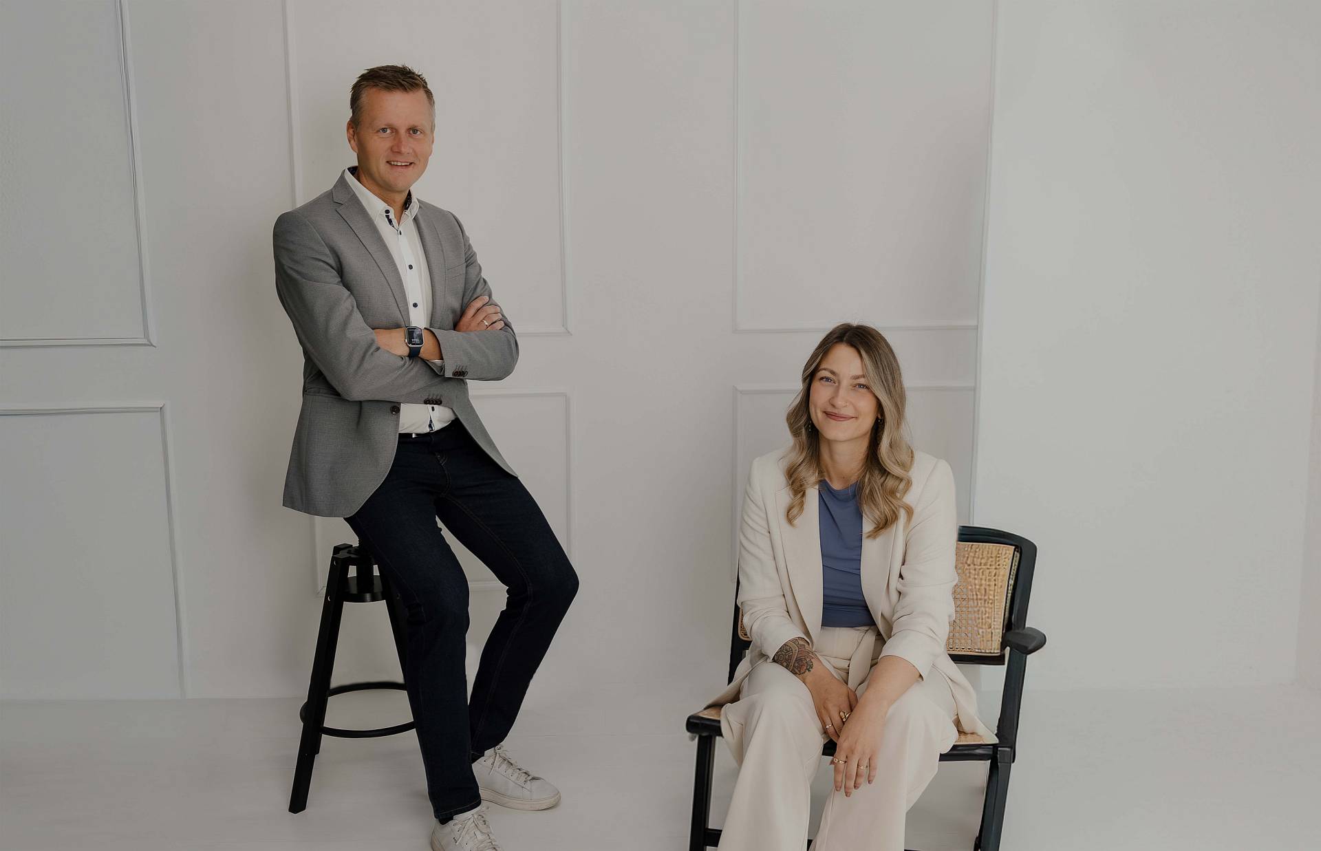 Peter Vogt und Mitarbeiterin lächelnd vor weißer Wand – das Team von Peter Vogt stellt sich vor.