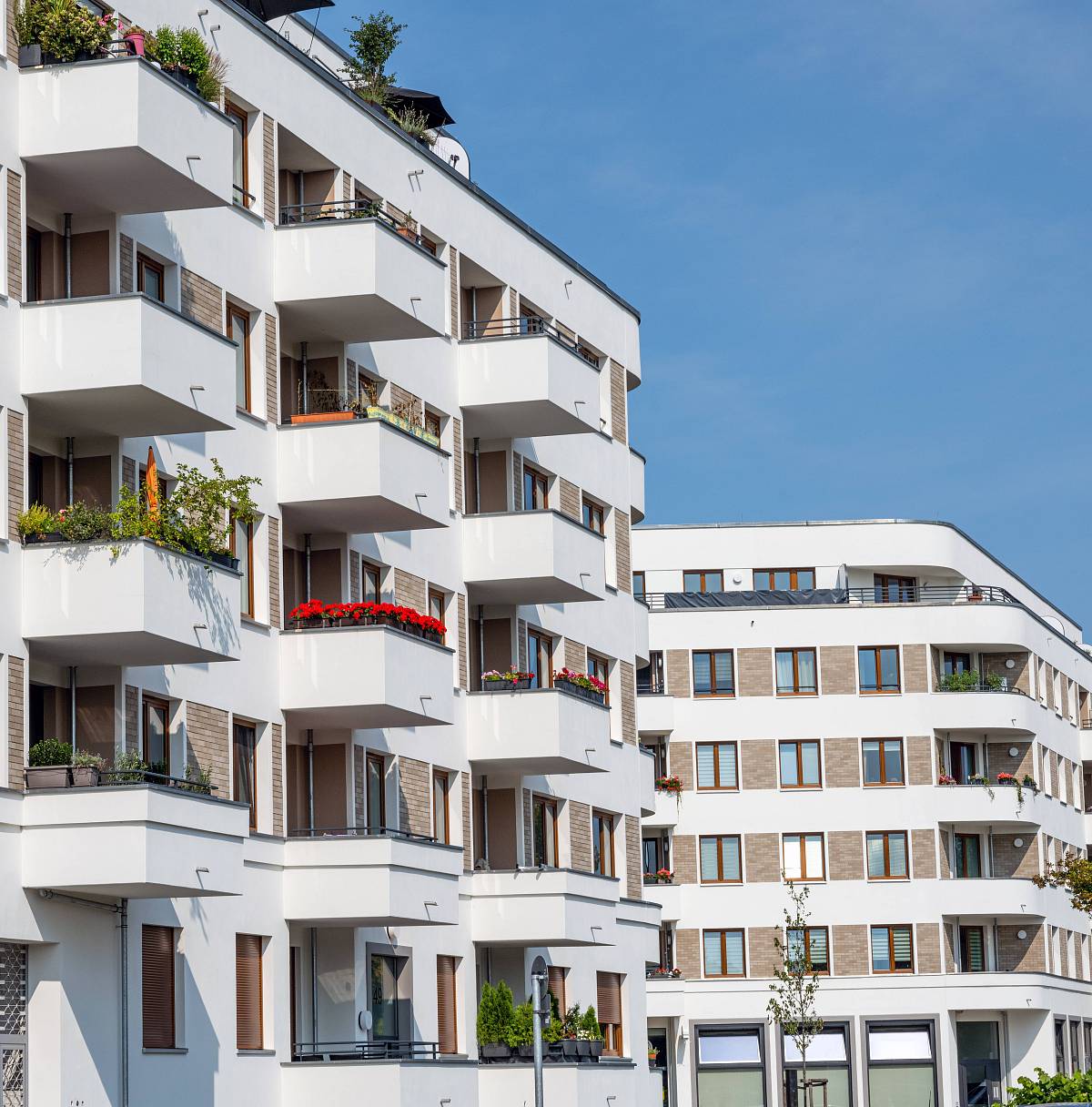 Modernes Mehrfamilienhaus in Berlin mit Balkonen und begrünten Fassaden bei sonnigem Wetter – Symbol für professionelle Immobilieninvestments.