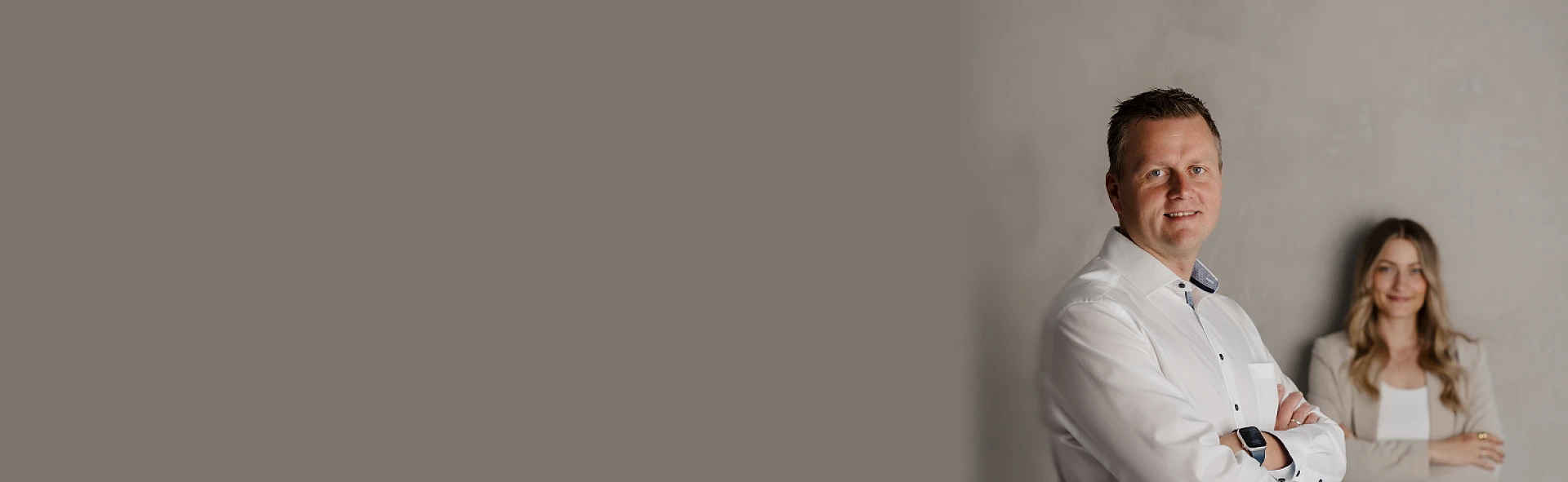 Peter Vogt mit Kollegin vor grauer Wand – professionelles Team von Peter Vogt Immobilien.