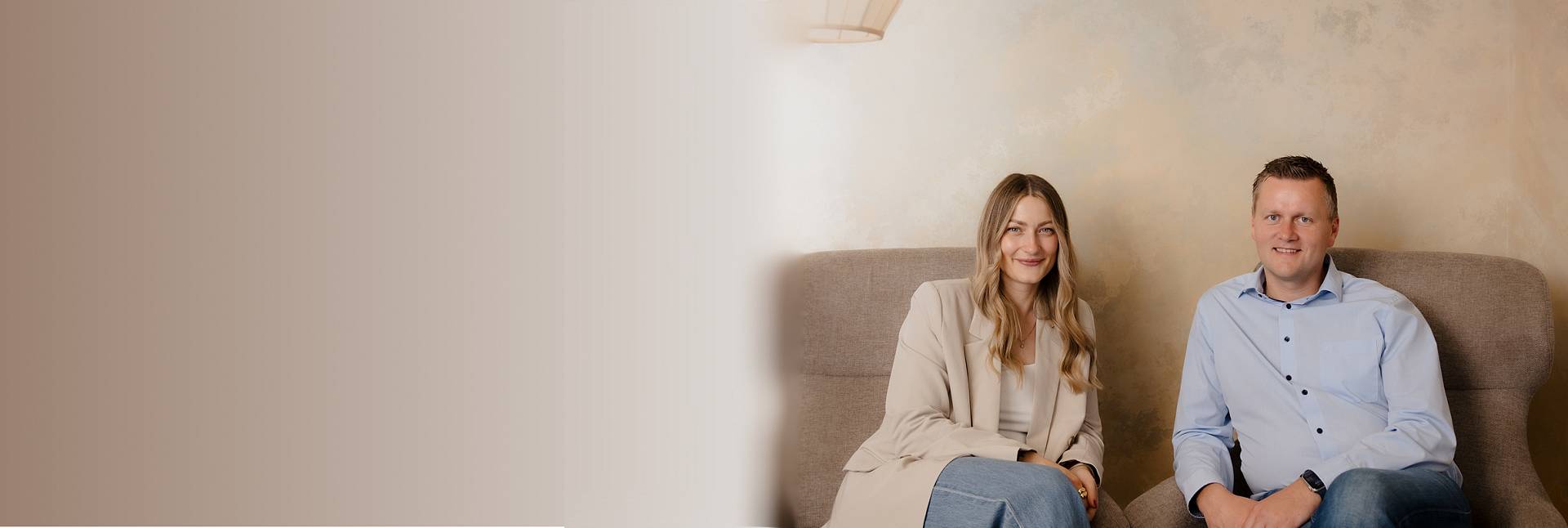 Zwei Immobilienberater sitzen gemeinsam mit Laptop in modernem Büro – freundliche Atmosphäre beim Beratungsgespräch